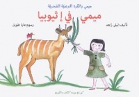 Une petite fille portant une robe verte tend des brins d'herbe à une gazelle.