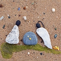 Quelques petits galets sur une plage forment des personnages en train de jouer