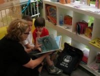 Une dame lit une histoire à deux enfants captivés.