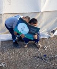 Des enfants lisent devant une tente à Kermanshah, après le tremblement de terre.
