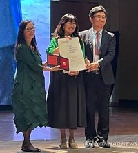 Suzy Lee reçoit le prix Hans Christian Andersen, accompagnée de Junko Yokota et de Minghzou Zhang. Copyright Yontap News KBBY